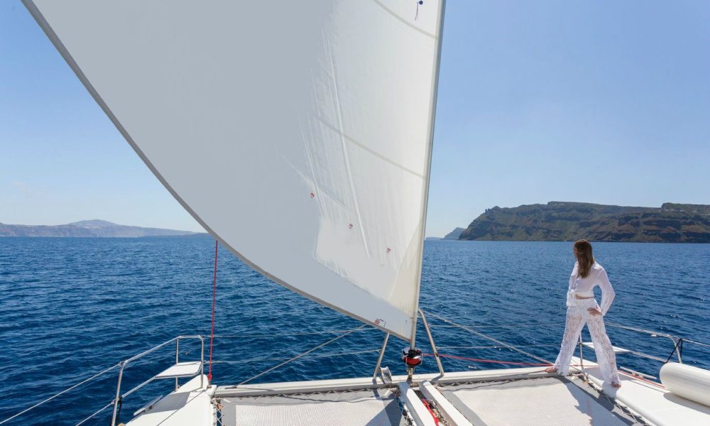 Female on board a catamaran gazing out into the Aegean sea, following our tips and the top things to do while sailing.