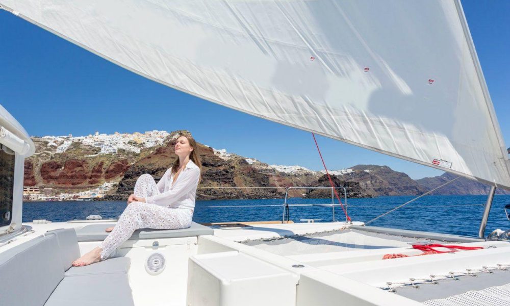Guest on board basking in the sun while discovering all the top locations of hidden Santorini with Spiridakos Sailing Cruises.
