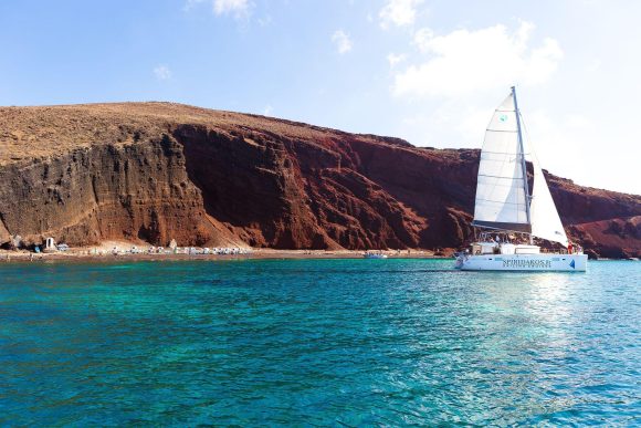 Sailing past the Red beach during the best time for Santorini cruise excursions