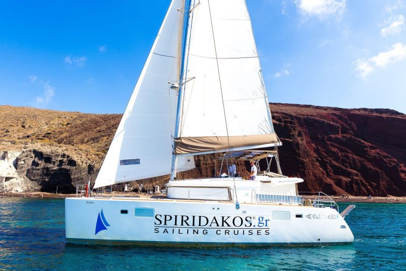 Sailing past the Red beach, one of the main reasons to go on a sailing cruise in Santorini