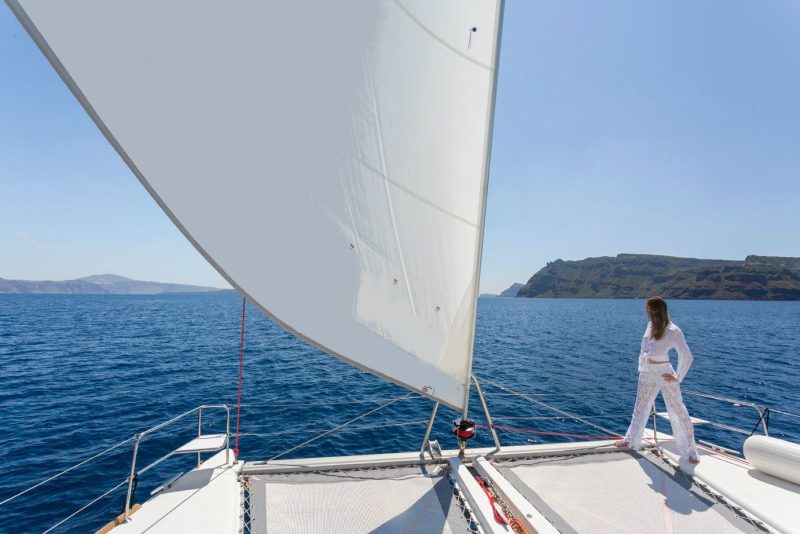 Female on board a catamaran gazing out into the Aegean sea, following our tips and the top things to do while sailing.