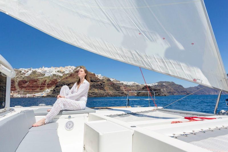 Guest on board basking in the sun while discovering all the top locations of hidden Santorini with Spiridakos Sailing Cruises.